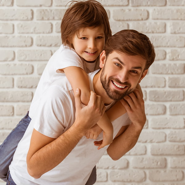A man and a child smile together, posing for the camera in a cheerful moment