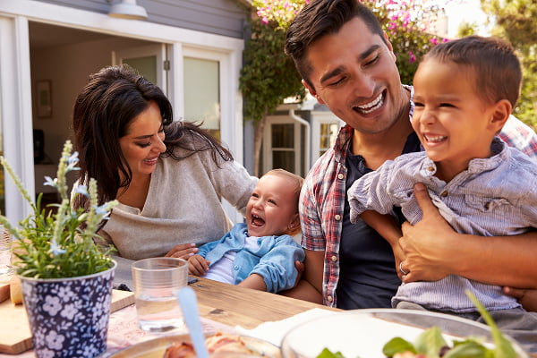 A family gathered around a table enjoying a salad and a glass of wine together
