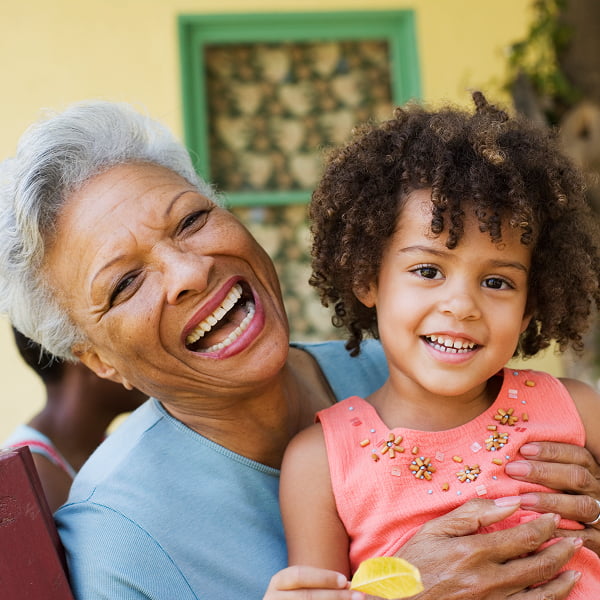 An older woman and a young girl smile together, showcasing a warm and joyful moment between generations