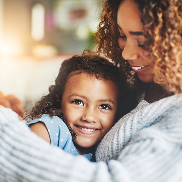 A woman smiles while holding a baby in her arms, radiating warmth and joy