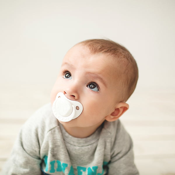 A baby with a pacifier resting on his face, looking content and relaxed