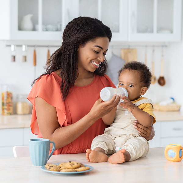 A mother is feeding her infant with a bottle, highlighting a tender bonding experience