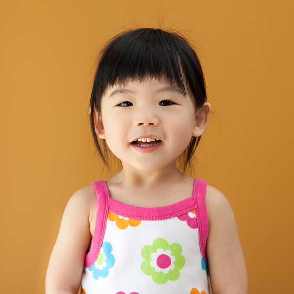 A little girl in a vibrant dress smiles joyfully, radiating happiness and innocence