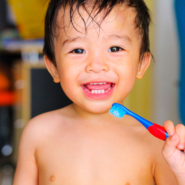 A young boy brushes his teeth with a toothbrush, focusing on his dental hygiene in a bright bathroom setting