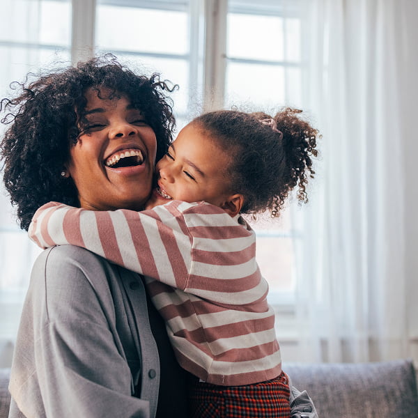 A woman and her daughter share a joyful moment, laughing together in a warm and loving atmosphere