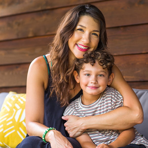 A woman and a young boy are seated on a couch, sharing a moment of relaxation and connection