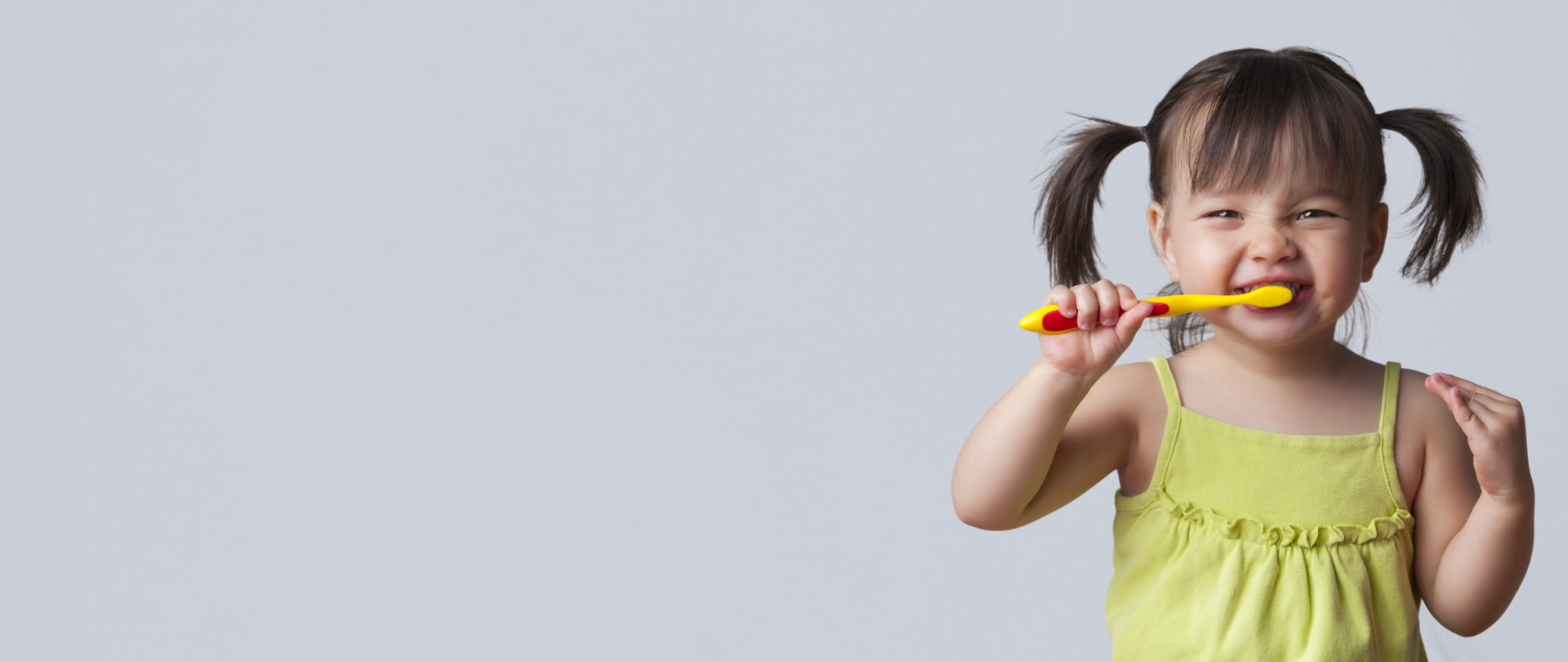 A young girl brushes her teeth with a toothbrush, focusing intently on her dental hygiene routine